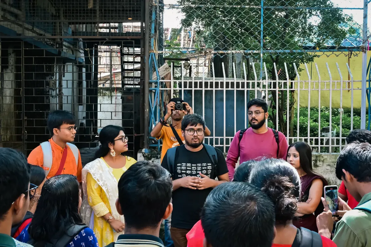 A diverse group of adults gathers for a photowalk in urban Kolkata, India.